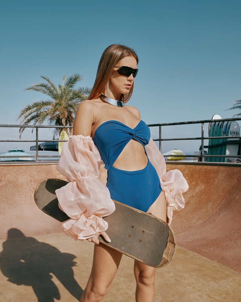Model in blue swimwear holding skateboard inside skate bowl for KINI Produksi fashion editorial.