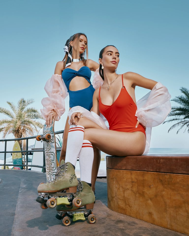 Two models in red and blue swimwear with skateboard and roller skates at Bali skatepark for KINI Produksi editorial.