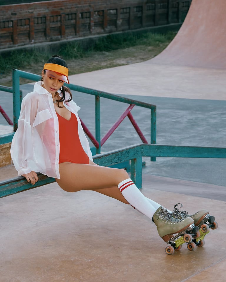 Model in red swimwear and orange visor sitting at Bali skatepark for KINI Produksi editorial.