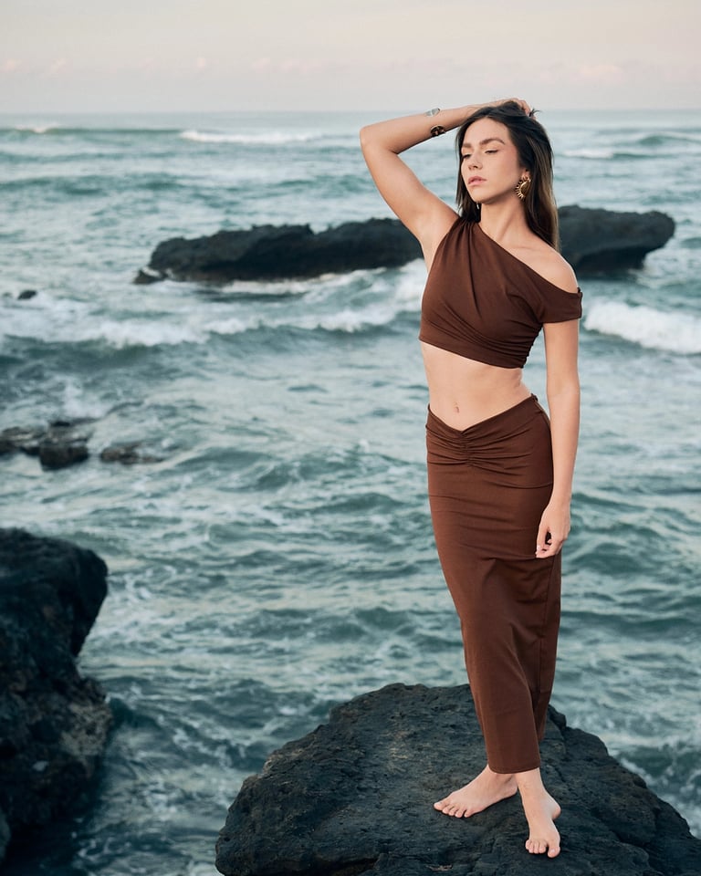 Editorial pose on black volcanic rocks by ocean, Kini Produksi lookbook.