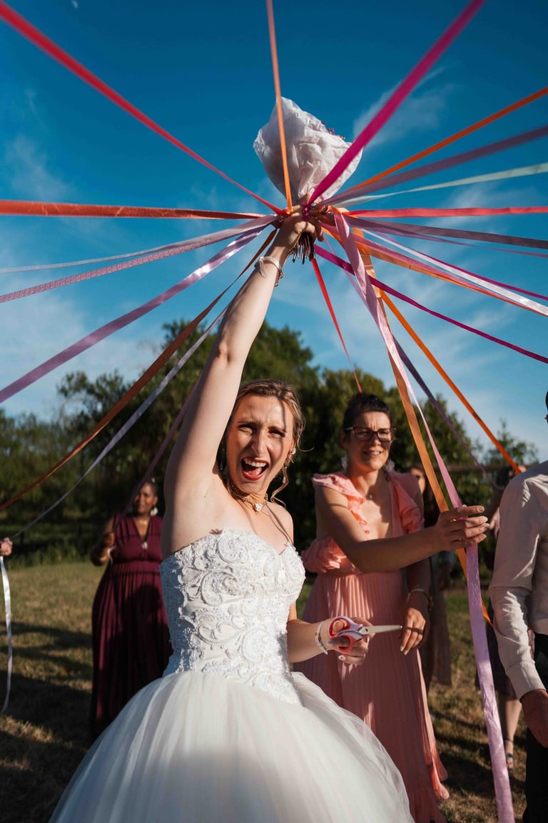 Une mariée tient des rubans colorés au-dessus de sa tête lors de la traditionnelle cérémonie de lancer de bouquet