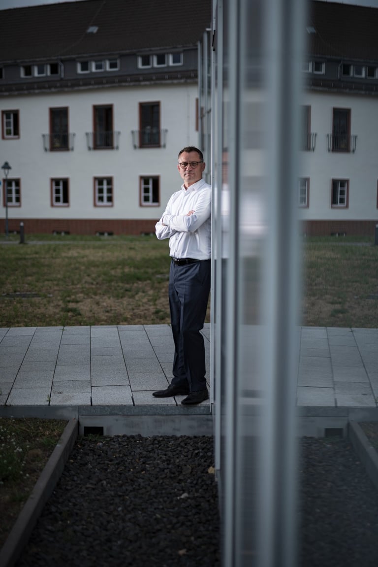 Businessportrait eines Unternehmers in Oranienburg mit verschränkten Armen vor moderner Architektur