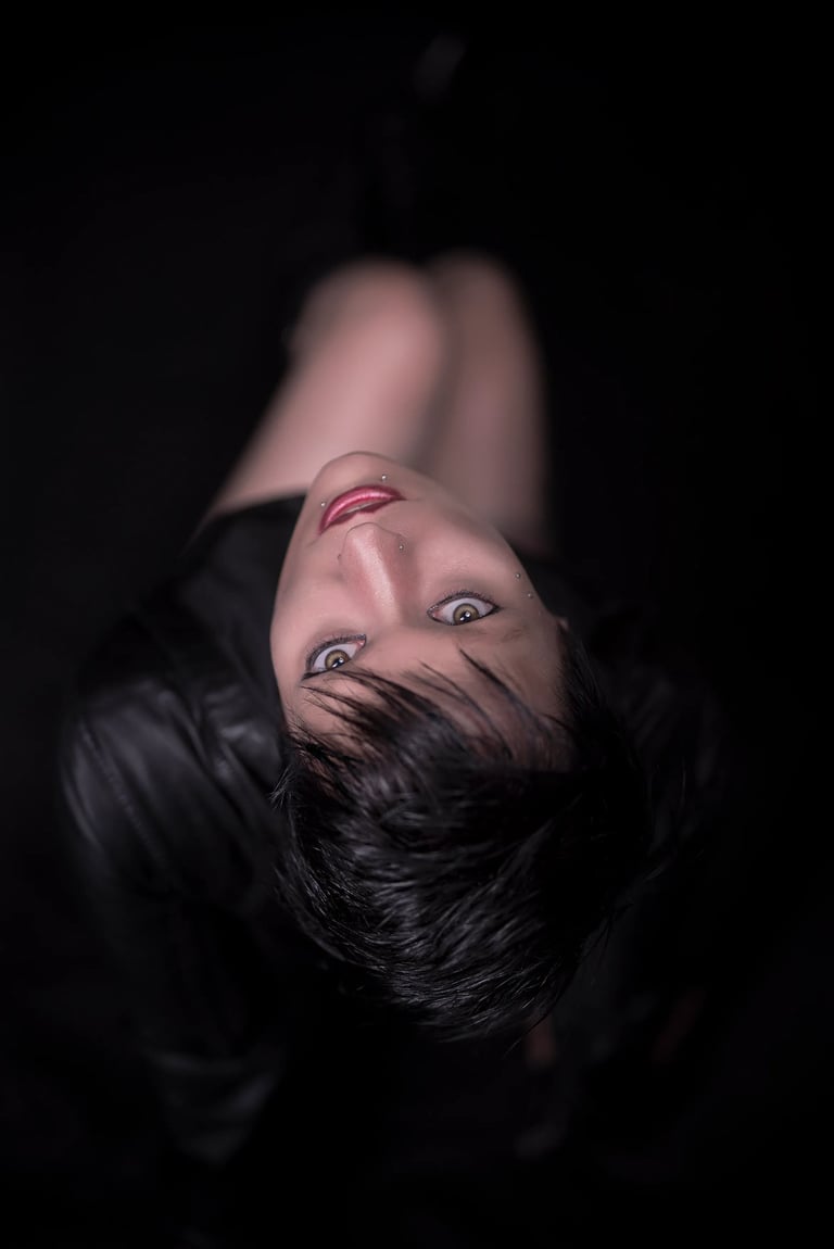 Blick von oben auf eine Frau mit kurzen dunklen Haaren, die nach oben schaut, mit auffälligen Augen und Lippen.