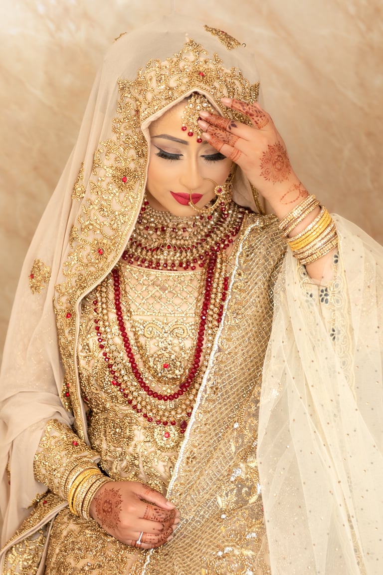 asian bride wearing traditional gold dress and traditional jewellery, getting ready putting her jewellery on