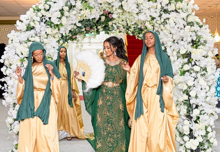 Somalian bride walking into venue with bridesmaids, all in vibrant traditional dresses, all happy and dancing
