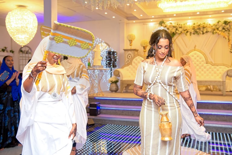 Happy Somalian bride dancing with bridesmaids, all dressed in traditional white & gold dresses, light & airy photo