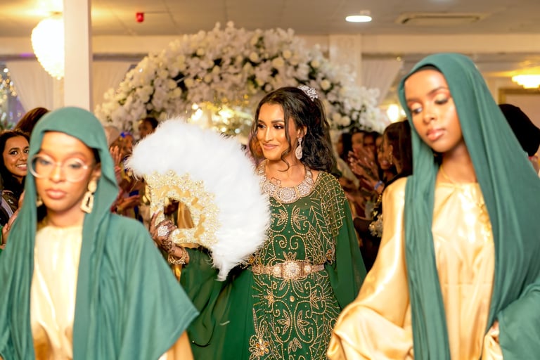 Smiling Somalian bride entering wedding venue with bridesmaids, all in traditional green & gold dresses