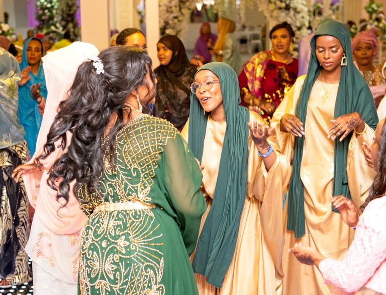 Somalian bride dancing with happy bridesmaid, both in traditional gold & green dresses
