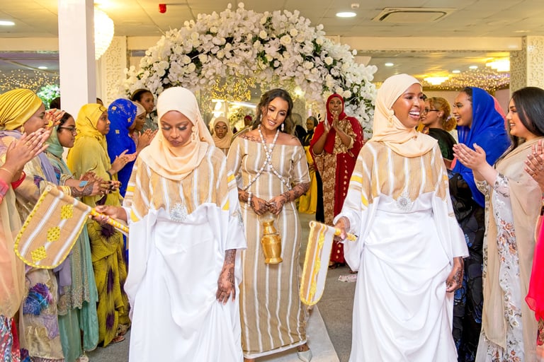Somalian bride & bridesmaids all dressed in traditional white & cream outfits dancing and laughing