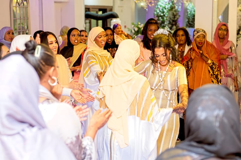 Happy Somalian bride dancing with bridesmaids, all dressed in traditional white & gold dresses, light & airy photo
