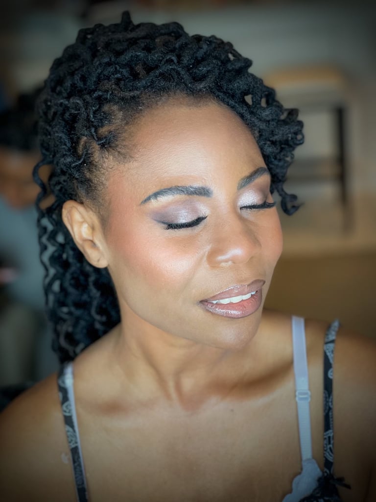 Black bride with twisted hairstyle, soft-glam wedding makeup, shimmery eyeshadow, glowing skin, long lashes, and glossy lips.