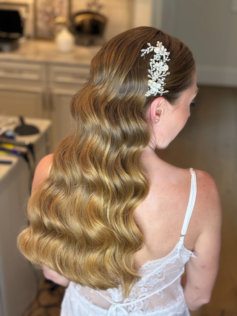 Bride with long blonde hair in Hollywood waves wearing jeweled floral hairpiece, glamorous bridal hairstyle for wedding.