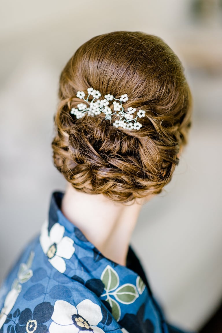 Bride with braided updo hairstyle adorned with pearl floral hairpiece, elegant and timeless look for wedding day inspiration.