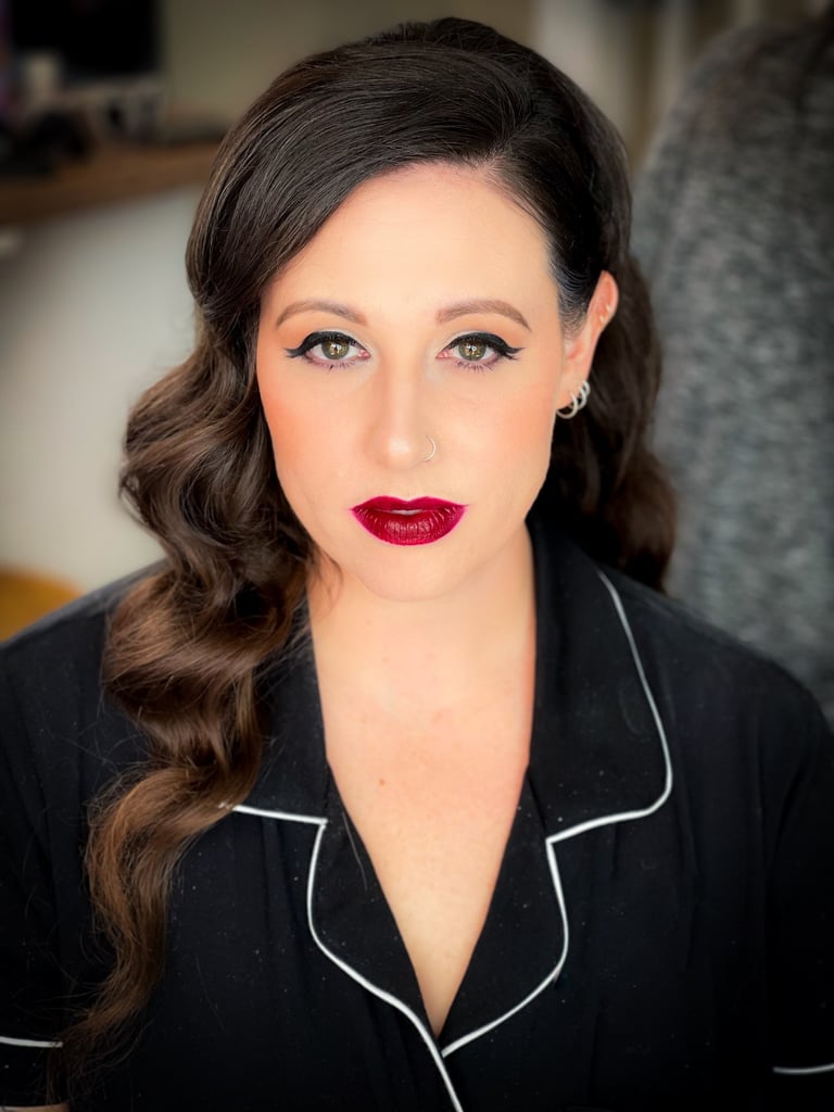Bride with glam waves, winged eyeliner, glowing skin, and bold red lipstick for a glamorous wedding makeup look.