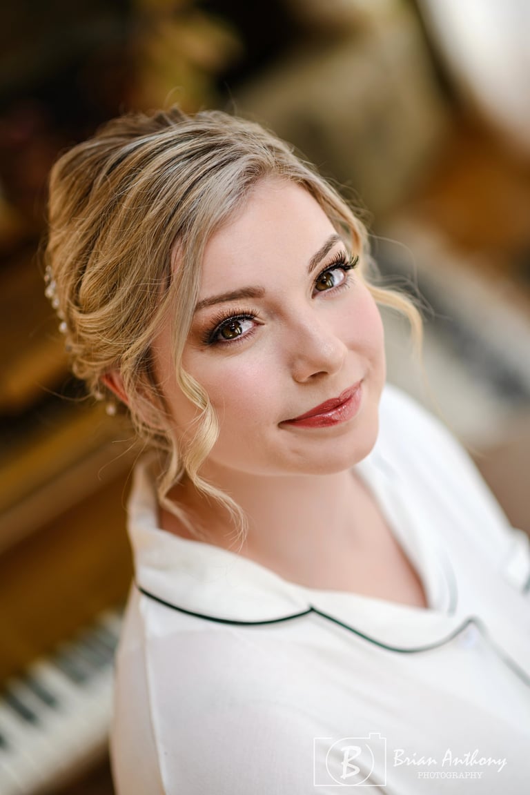 Bride with natural wedding makeup featuring soft lashes, glowing skin, and subtle lipstick, smiling in bridal portrait.