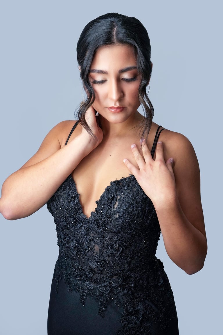 Woman with sleek center-part updo and soft curls framing face wearing black lace gown, elegant makeup for formal event.