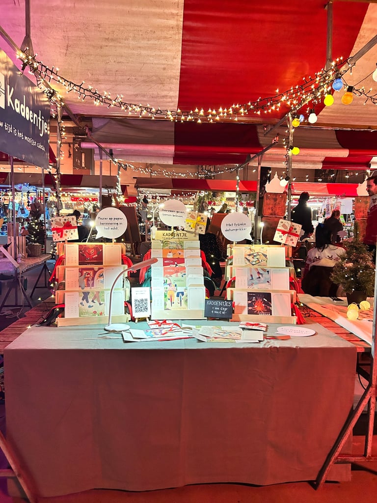 Feestelijke kraam op Kerstmarkt met rekken met Kadoentjes en feestelijke lampjes