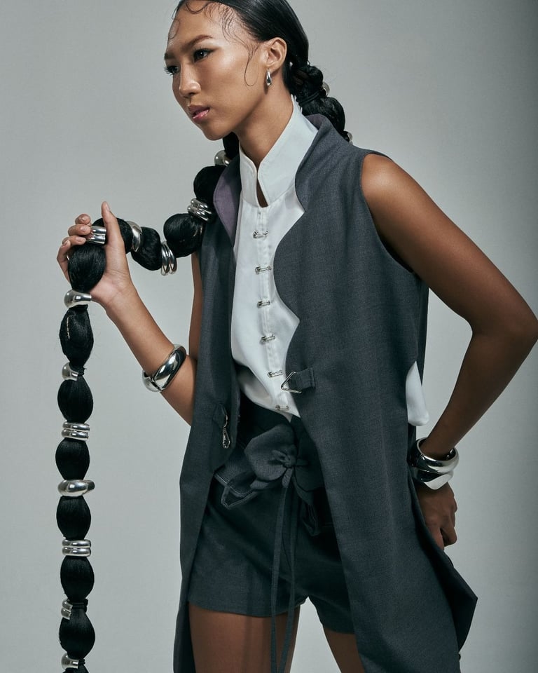 Model in structured Korean-inspired clothing poses while holding her long hair.