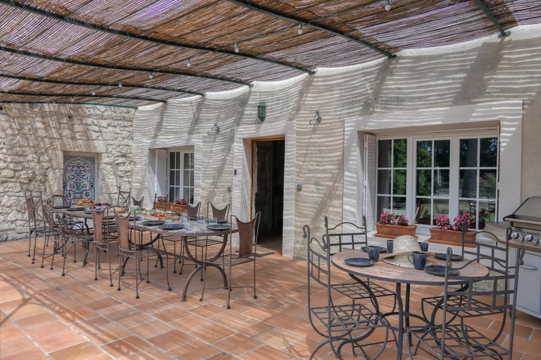 Charming Provencal terrace with mosaic table and whrought iron chairs, perfect for dining in L'Enclos du Soleil le Vent