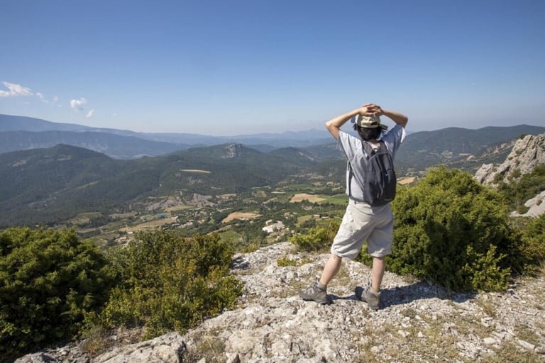 Hiker on a mountain trail in Buis-les-Baronnies with views of nearby hills and valleys