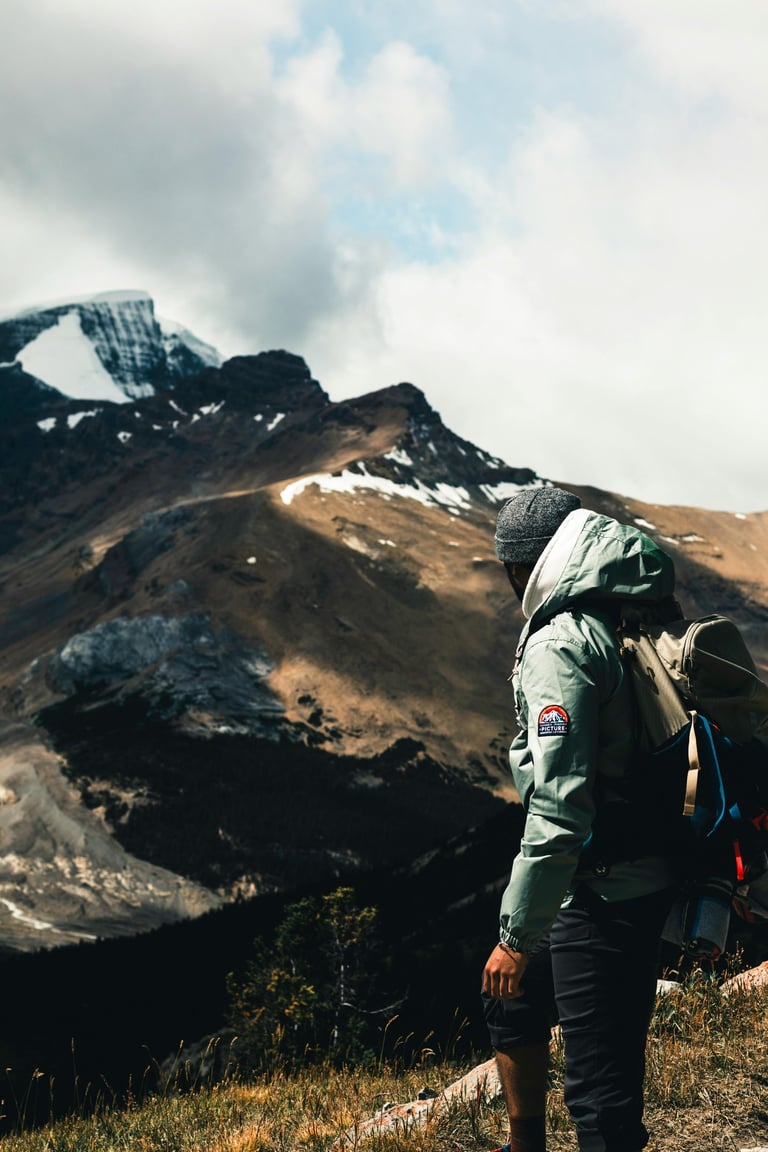 un homme en montagne qui porte une veste un sac à dos un bonnet
