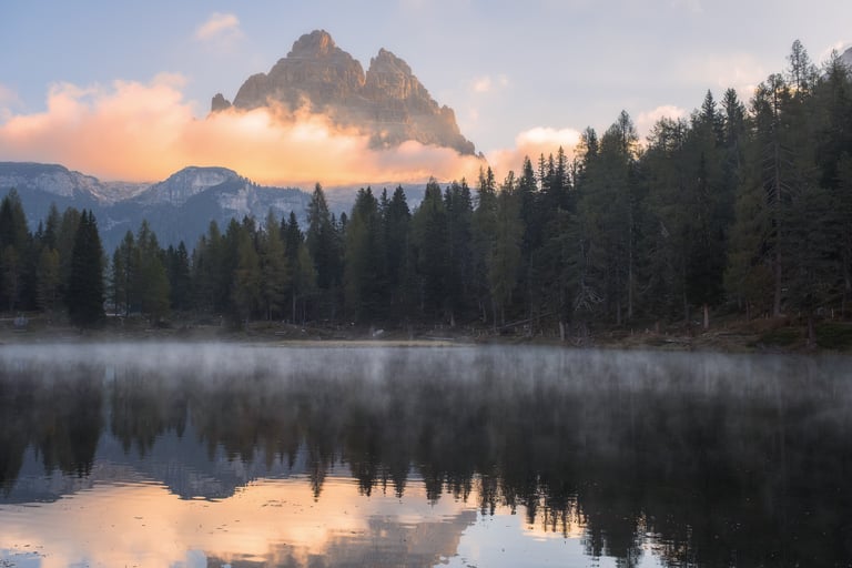 Tre Cime di Lavaredo e bosco che si riflettono sul lago Antorno all'alba