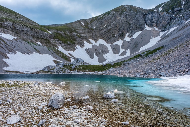 Lago di Pilato parzialmente ghiacciato e montagne sullo sfondo