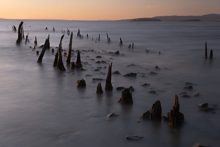 Lunga esposizione al Tramonto sul Lago Trasimeno con pali che fuoriescono dall'acqua