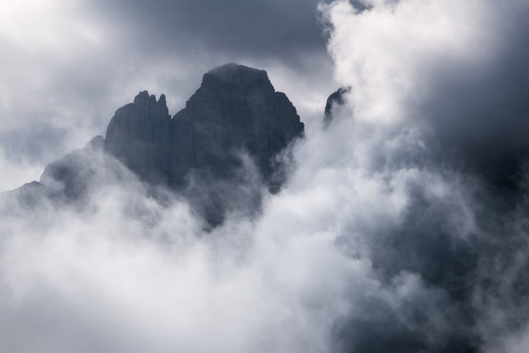 Nuvole illuminate dal sole che si aprono mostrando una vetta delle Dolomiti