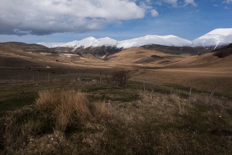 Vette dei Monti Sibillini innevate e prati sottostanti giallastri,