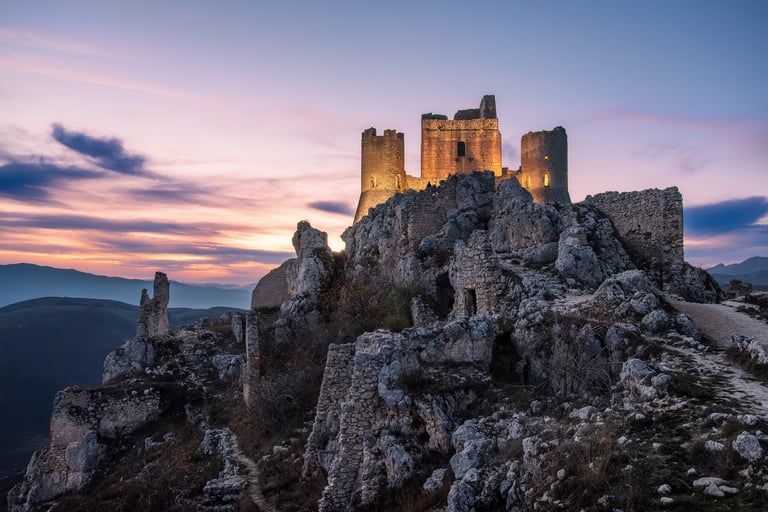 Castello di Rocca Calascio al tramonto illuminato con luci artificiali, cielo colorato sullo sfondo
