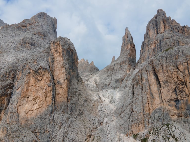 Fotografia aerea sulle rocciose vette dolomitiche delle Torri del Vajolet e cielo nuvoloso