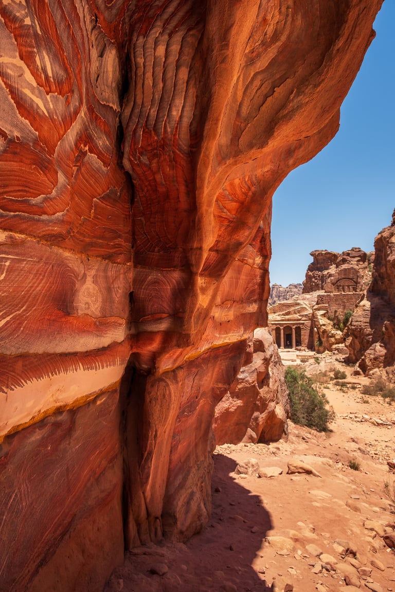 Parete rocciosa rossa a Petra con templio sullo sfondo