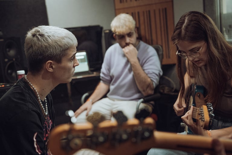 Three musicians collaborating in a recording studio at BIME Bilbao. Woman playing guitar, two men listening. Creative music s