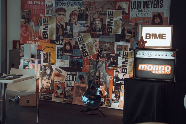 BIME Bilbao promotional display with posters, a guitar, a Mondo Sonoro amplifier, and a BIME sign. Music event promotion