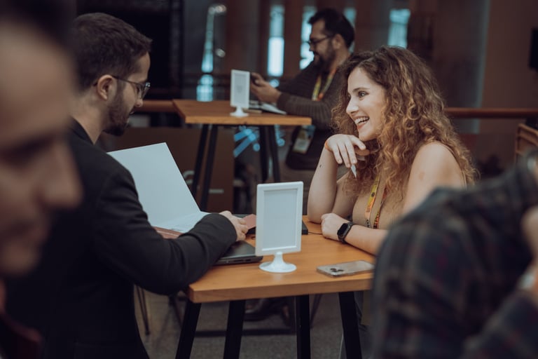 Two people networking at BIME Bilbao. A woman with curly hair is smiling while talking to a man with glasses. BIME name card 