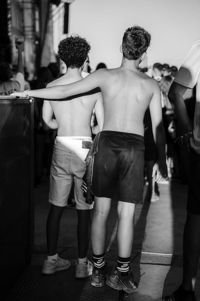 Black and white shot of two shirtless young men in shorts in the crowd at SONORAMA RIBERA in Bilbao. Music festival atmospher