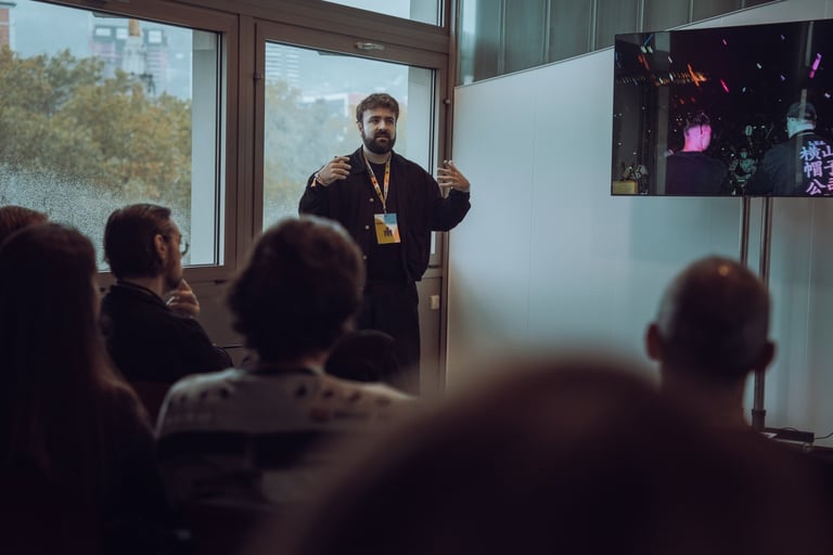 Speaker with a BIME lanyard presenting to an audience at BIME Bilbao. Screen displaying a video. Conference or workshop setti