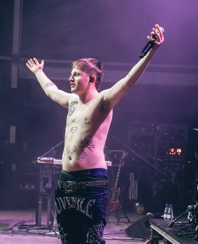 Dillom artist with tattoos performing on stage with a microphone at SONORAMA RIBERA. Live music.
