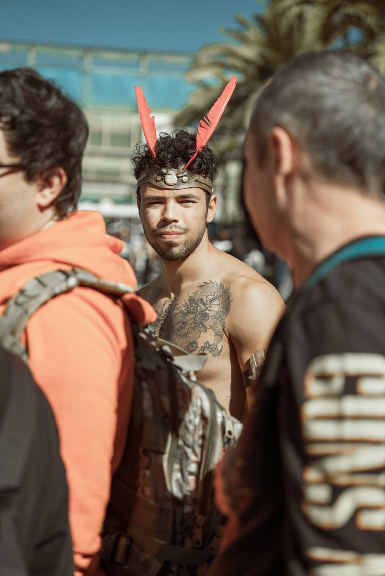 Man with tattoos and red feather headpiece at IFEMA Madrid. Unique convention costume