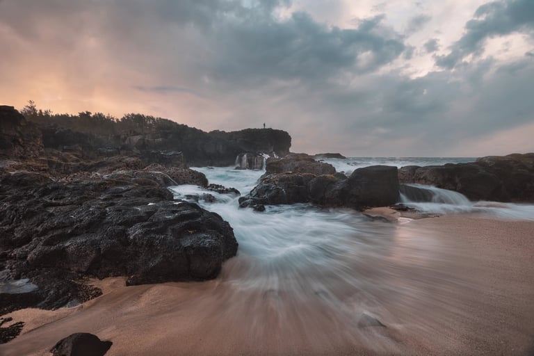 Waves flowing over rocks on the dramatic coastline of Le Souffleur at sunset in Mauritius