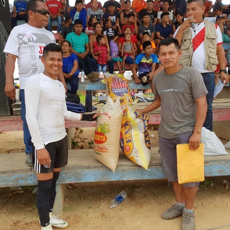 A community event in Peru with Roger Bardales holding large bags of rice for donation distribution.