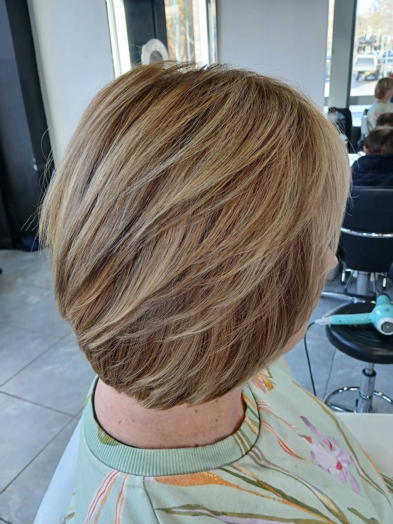 Layered blonde bob haircut with honey highlights and textured styling in a professional hair salon.
