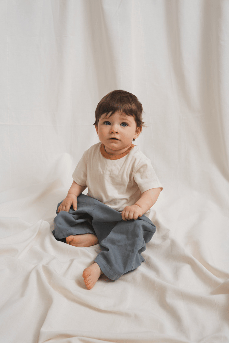 Small beautiful baby sitting in a studio in front of a textile background, editorial style picture.
