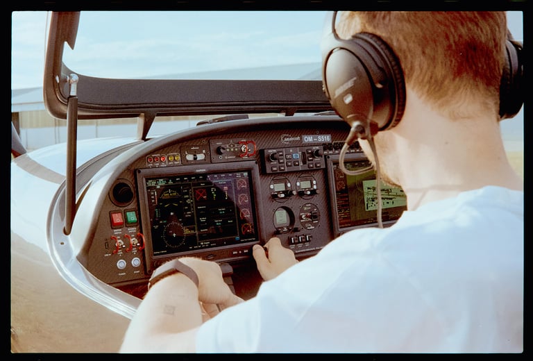 Man operating a private small airplane control panel, shot from behind.