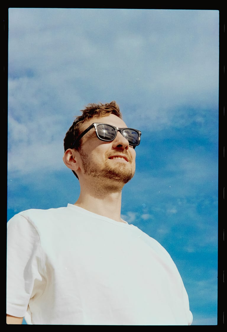 Young handsome man looking into distance with sunglasses on, low angle shot.