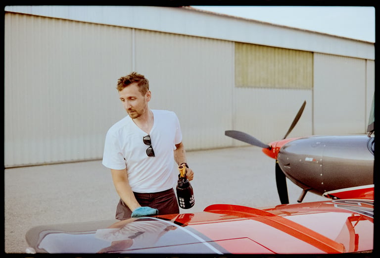 Young handsome pilot man cleaning private red airplane.