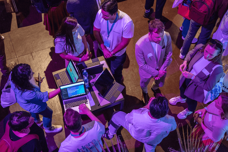 Top down shot of people at a tech event with computers talking.