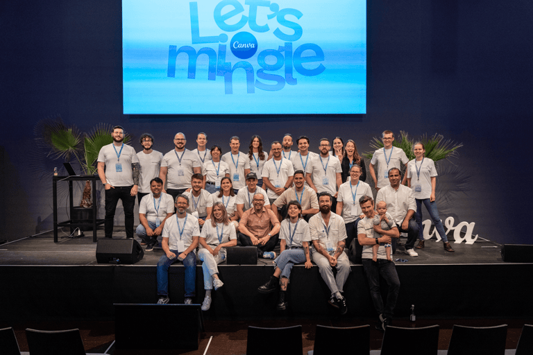 A group image of Canva company employees on a stage at an indoor conference in front of a screen.