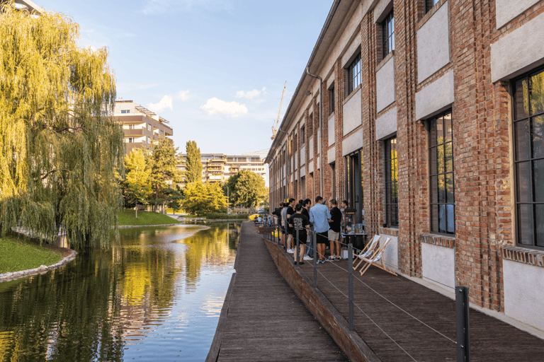 Group of people at an event in the distance on a veranda next to a water pond in the summer.